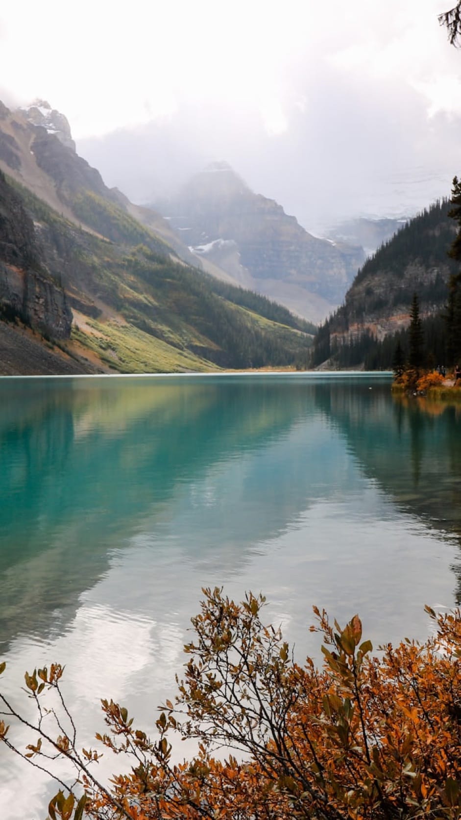 A turquoise mountain lake beneath misty peaks