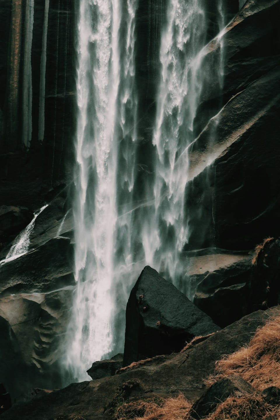 Vernal Falls seen closely through dark rock and spray